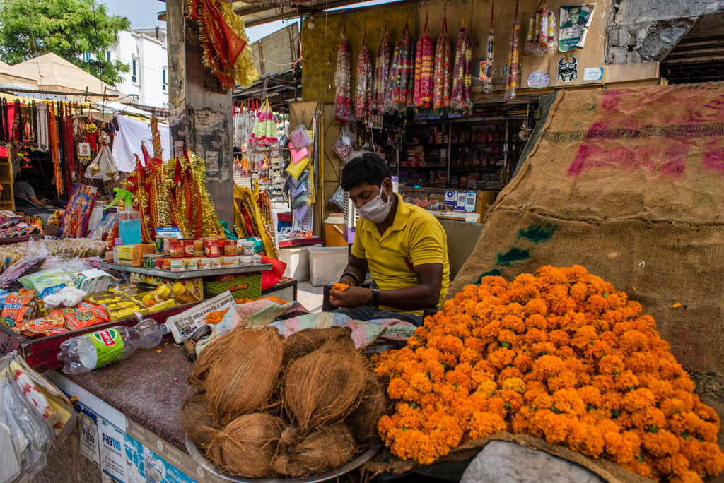 An Indian shopkeeper sells votive threads, coconuts and flower garlands on June 8, in Delhi, India.