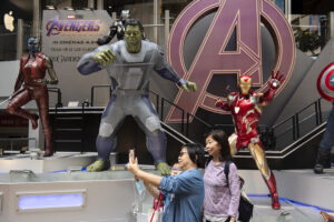 Pedestrians taking a selfie with Marvel figures