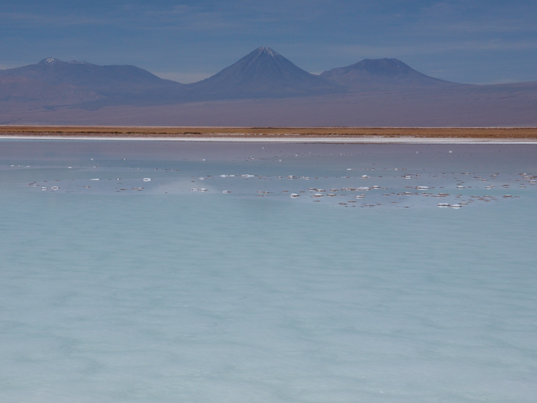 The large Laguna La Brava lake with active volcanoes behind at sunset.