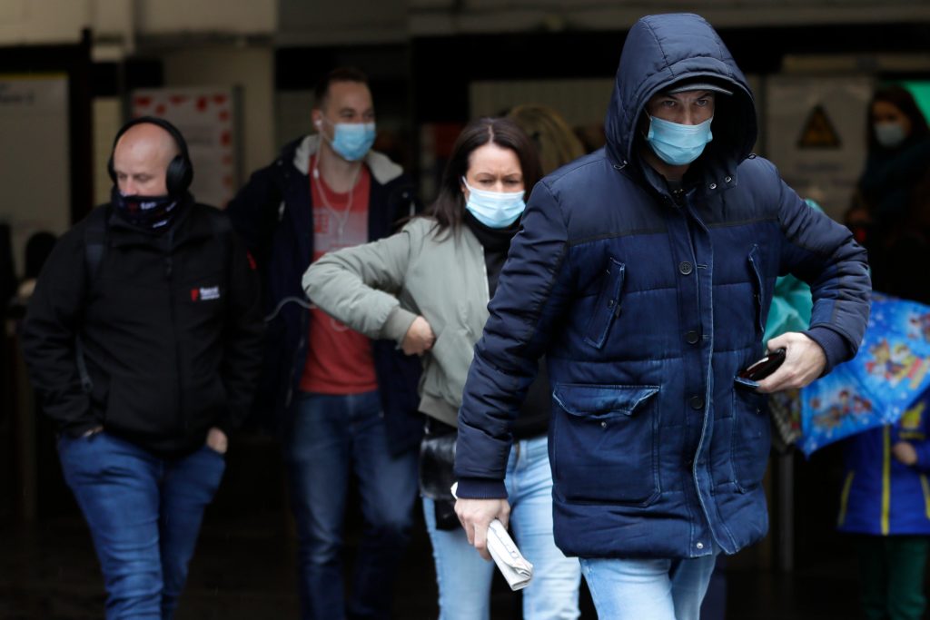 Commuters wear masks as they leave a tube station in London