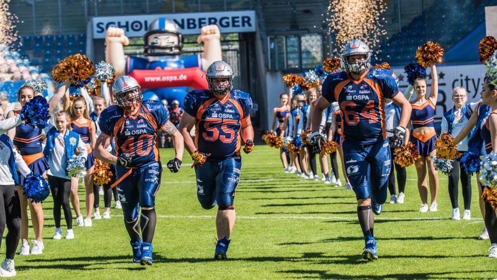 American Footballer der Rostock Griffins laufen unter Anfeuerungen von Cheerleaderinnen ins Rostocker Ostseestadion ein.