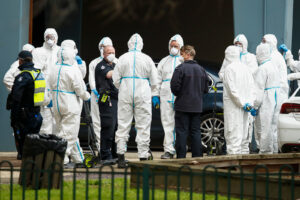 Workers in personal protective equipment are seen, along side police patrols, on July 7, in Melbourne, Australia.