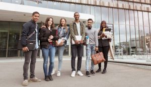 Eine diverse Gruppe Studierender vor einem Hochschulgebäude